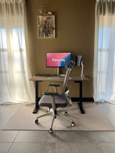 Last inn bildet i Galleri-visningsprogrammet, Pomelo kontorstol - grå stoff og lysegrå understell. En fremvisning fra showrommet der kontorstolen er satt sammen med en hev senk pult. Bilde fra langt avstand. 

